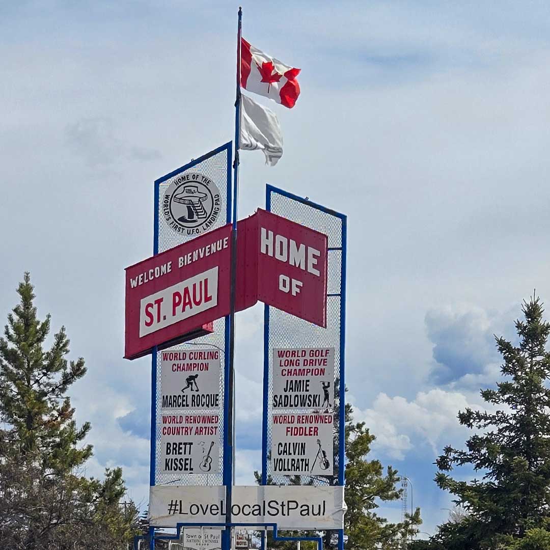 Canadian flag atop tall blue metal sign that says welcome to St. Paul
